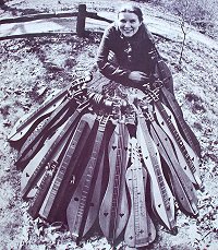 Jean Ritchie, surrounded by dulcimers from many fellow players and their families, just to show the variety that has been produced. Clicking the photo will take you to our history article.